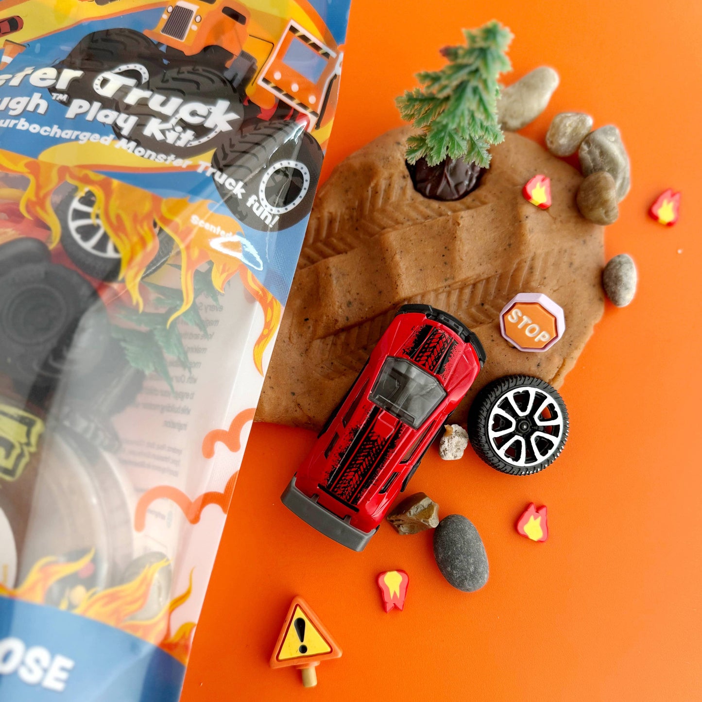 Toy truck and accessories on an orange background with packaging to the side