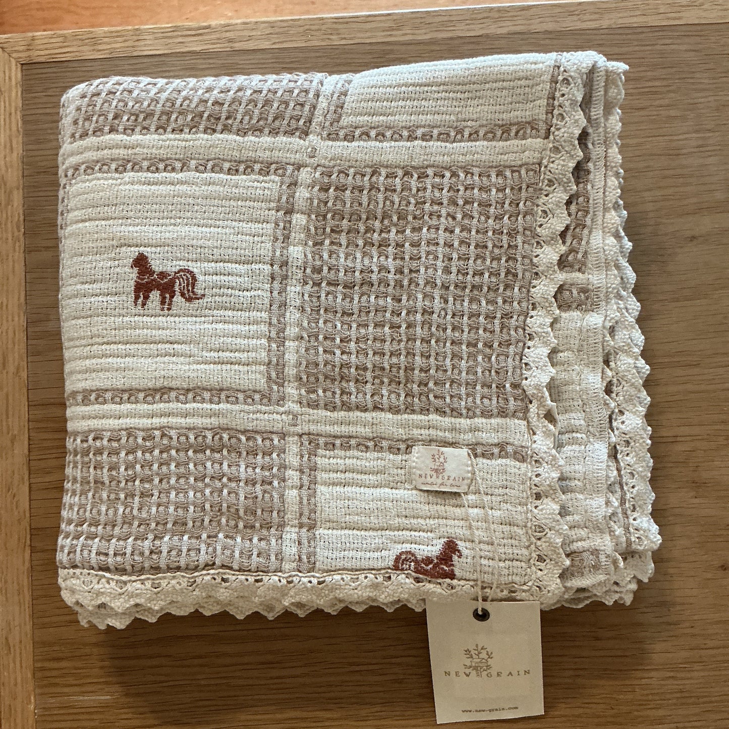 Textured fabric pouch with lace details and embroidered designs on a wooden surface