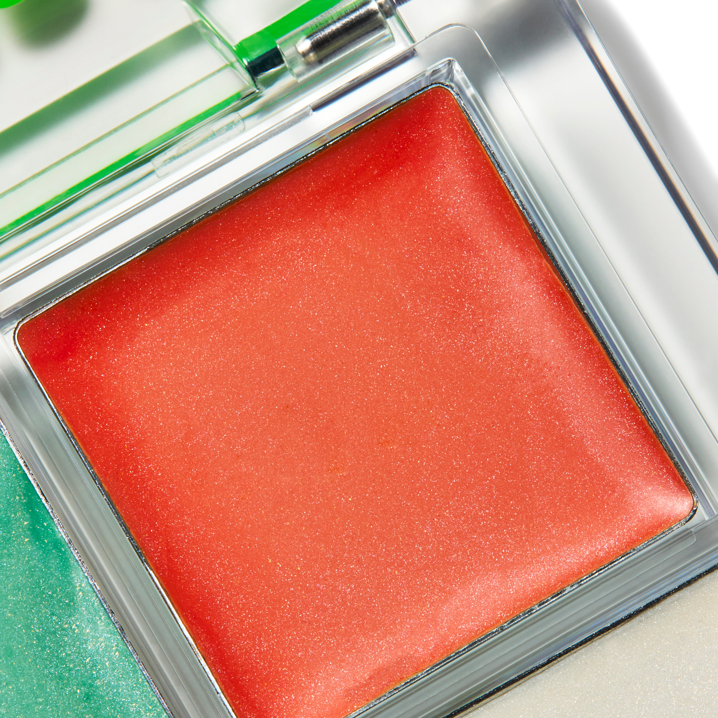 Red blush compact with a green mirror on a light background