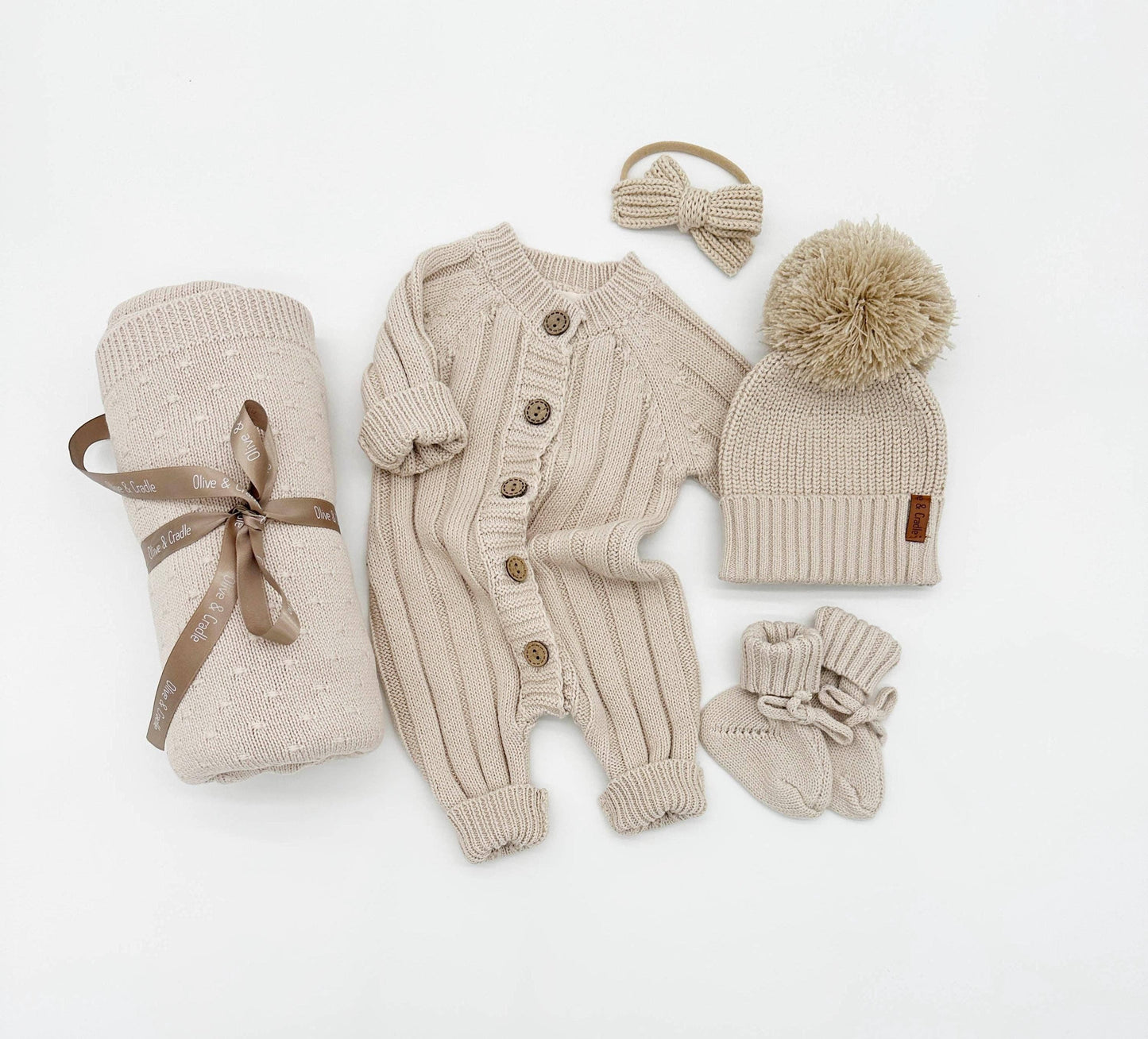 Beige baby outfit set with cardigan, pants, hat, and blanket on a white background