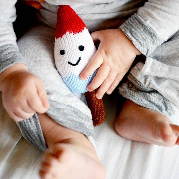 Children playing with a knitted gnome toy on a bed