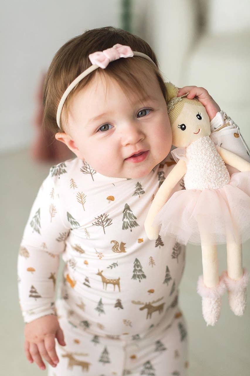 Baby holding a doll with a neutral background