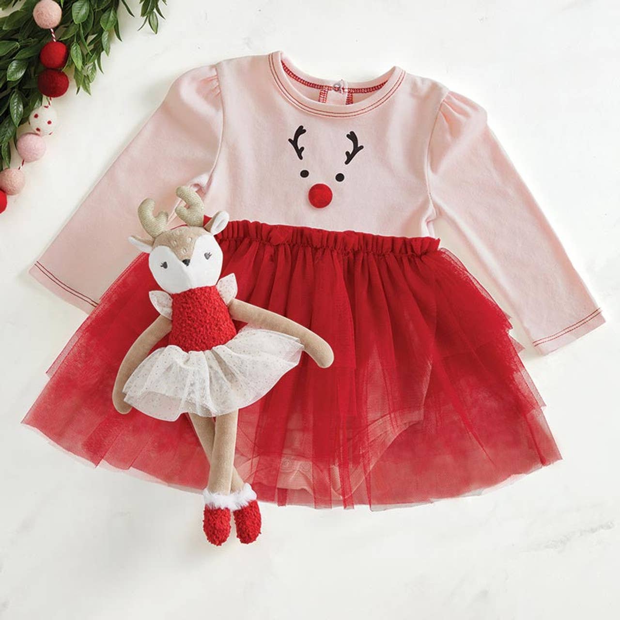 Children's dress with reindeer design and matching plush toy on a white background