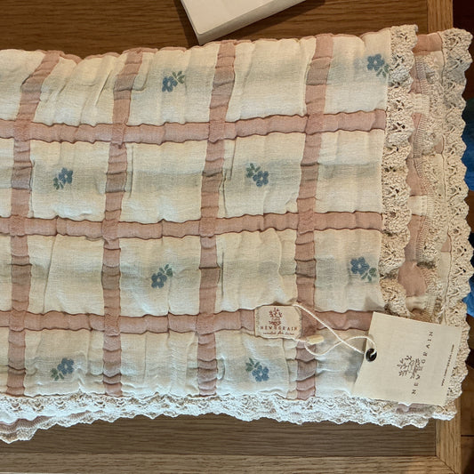 Floral-patterned fabric with lace trim on a wooden surface