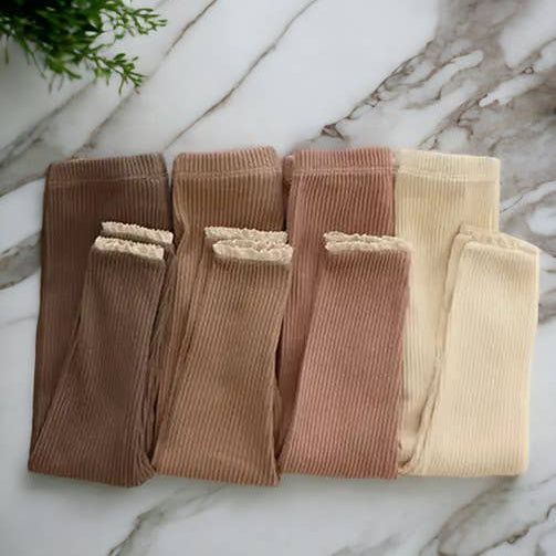 Set of four pairs of tights in brown and beige on a marble surface with decorative elements.