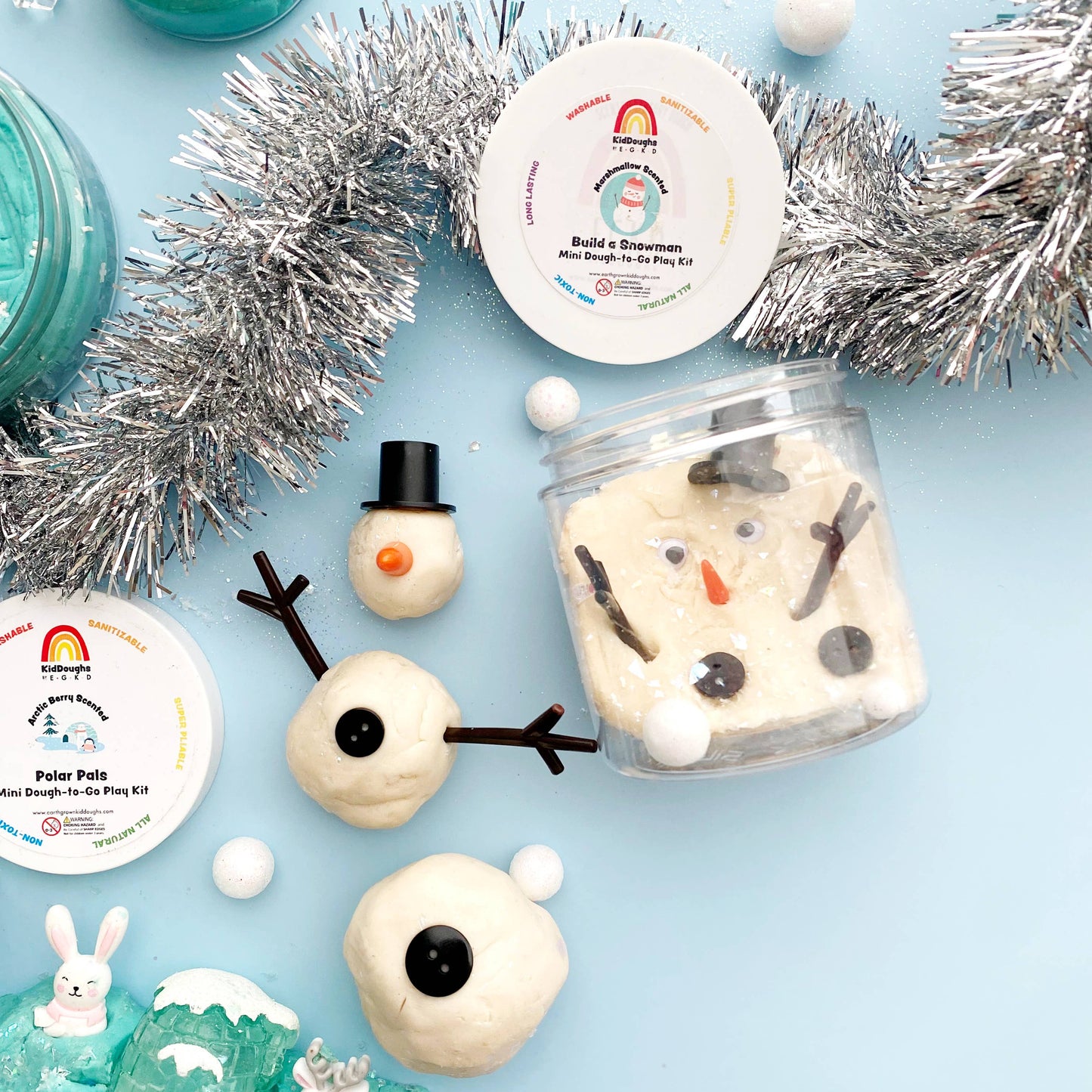 Snowman-themed play dough kit with decorative elements on a light blue background