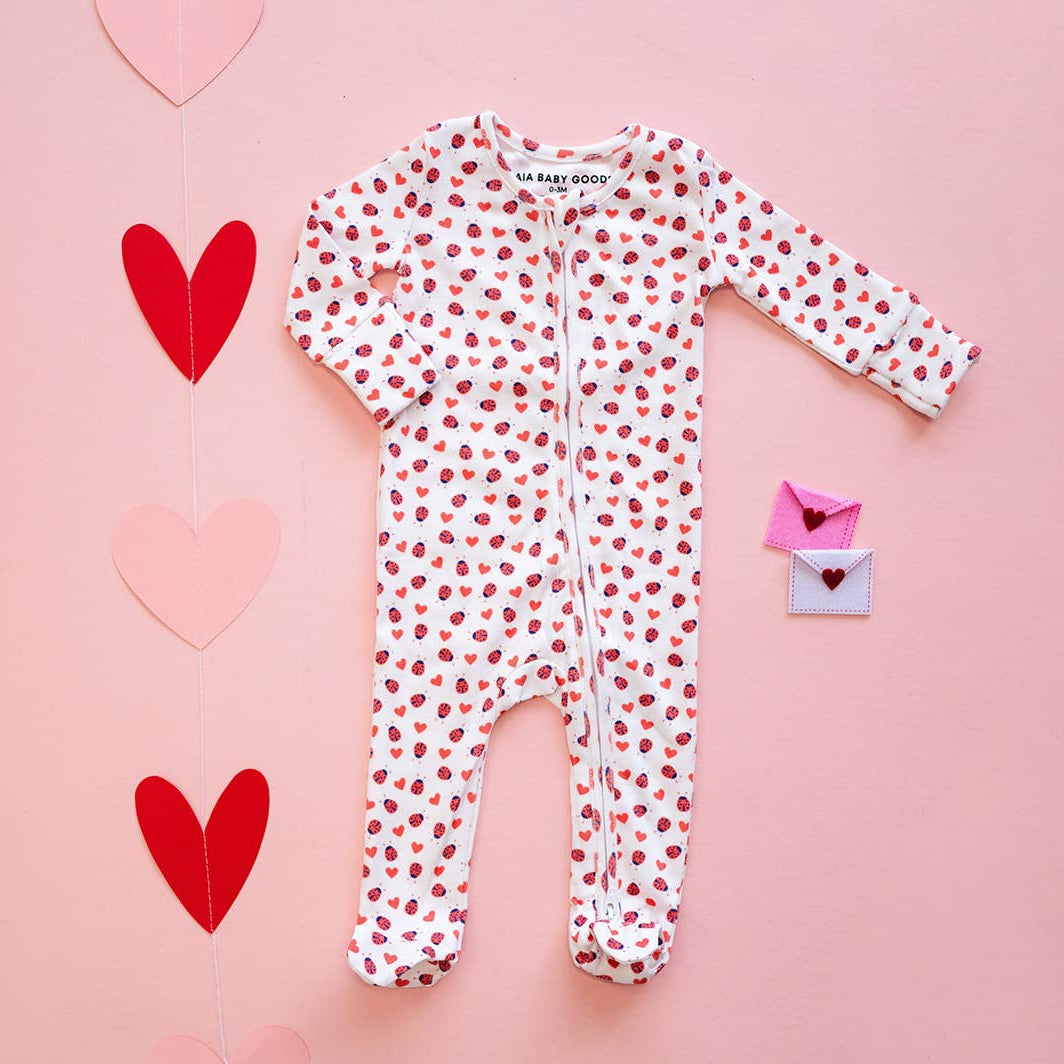 Baby onesie with heart pattern on a pink background with hearts