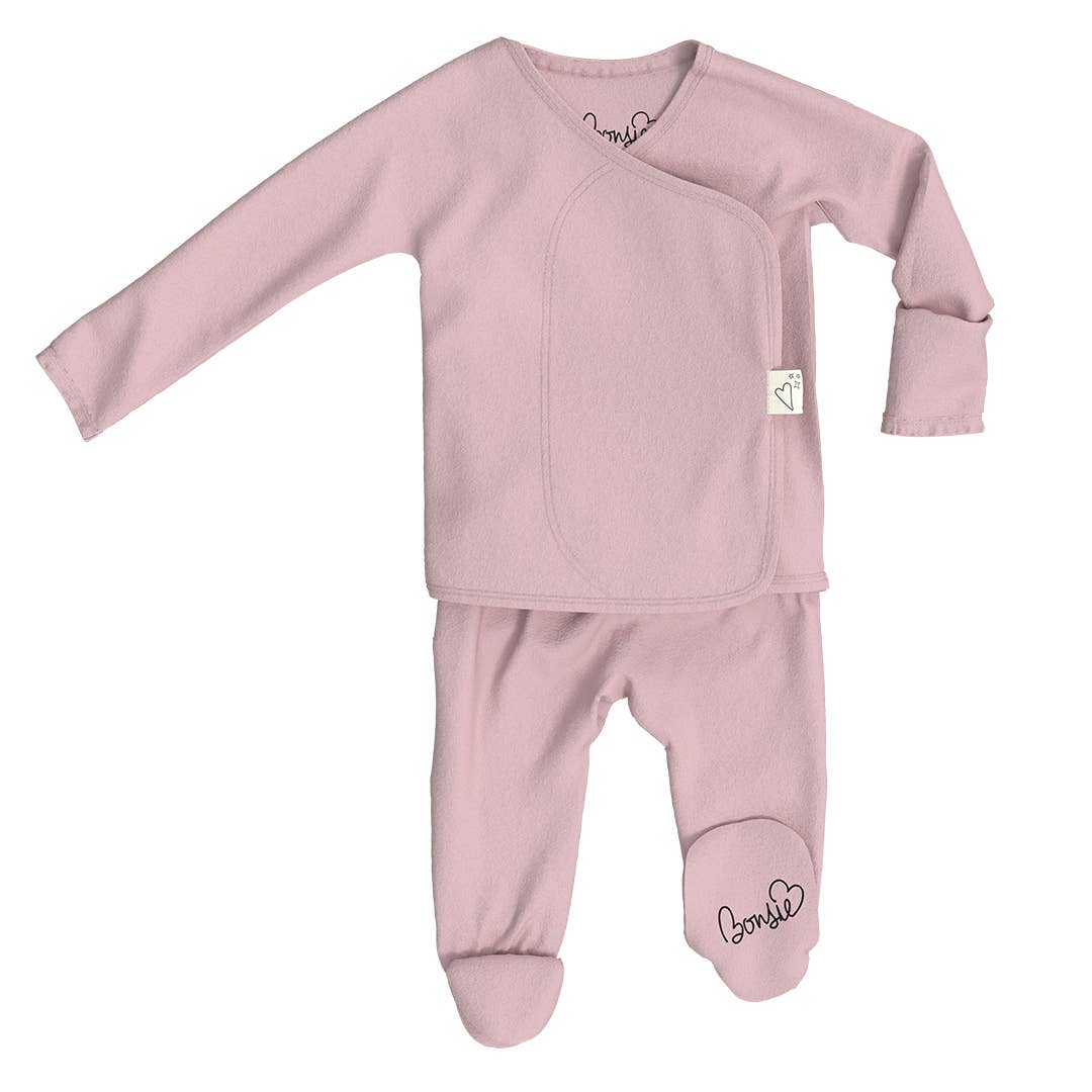 Pink baby outfit with long sleeves and footed pants on a white background