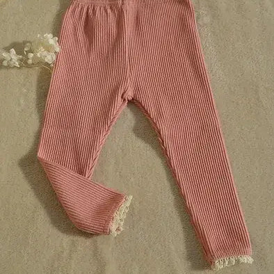 Pink ribbed leggings with lace trim on a beige surface