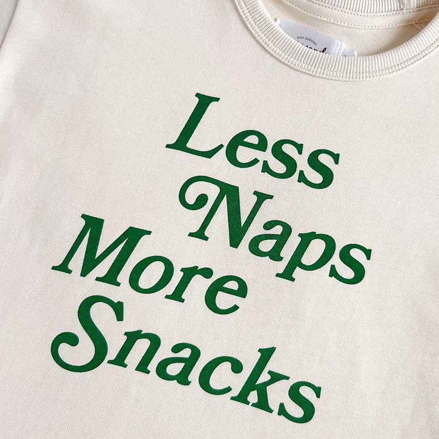 Beige shirt with green text 'Less Naps More Snacks' on a white background