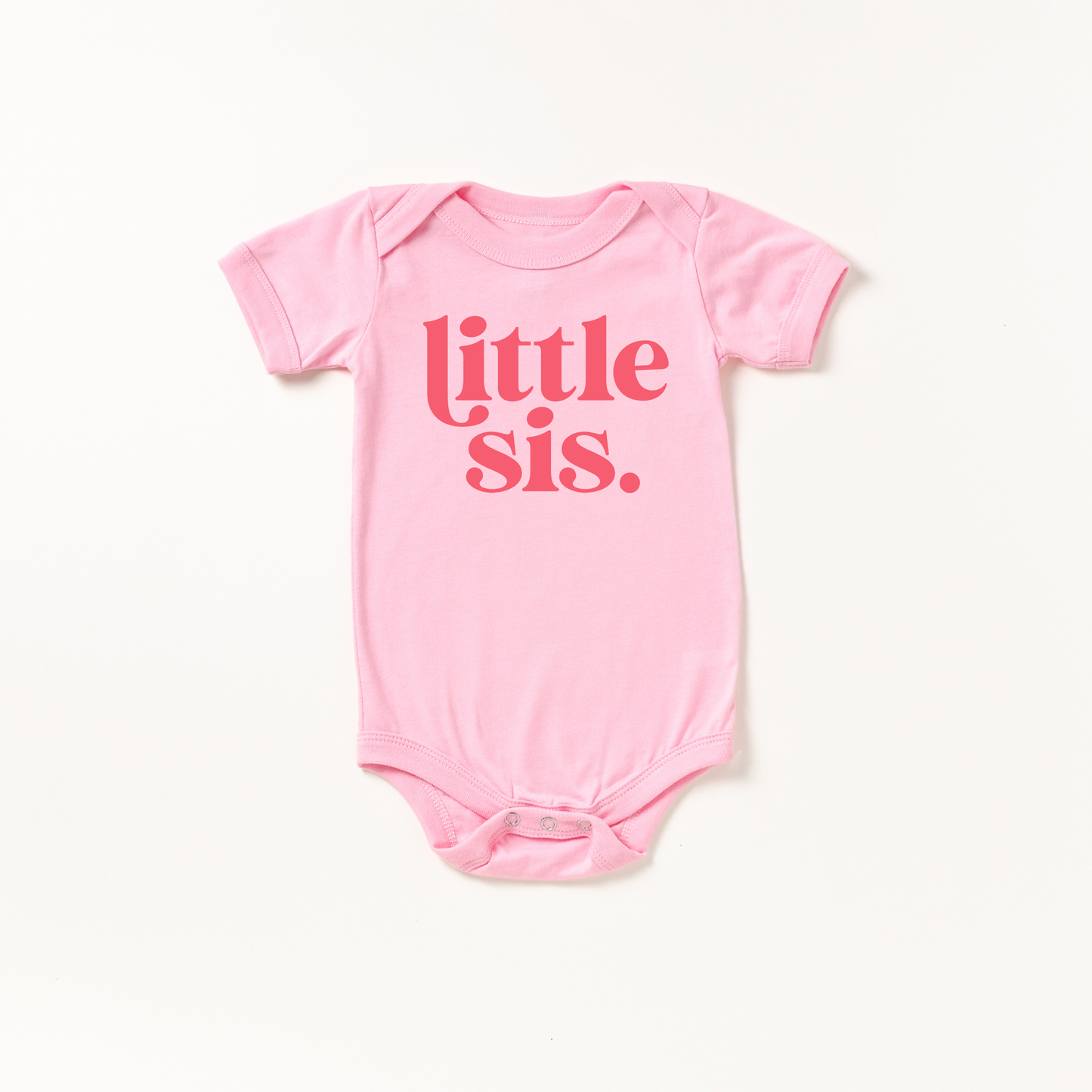 Pink baby onesie with 'little sis' text on a white background