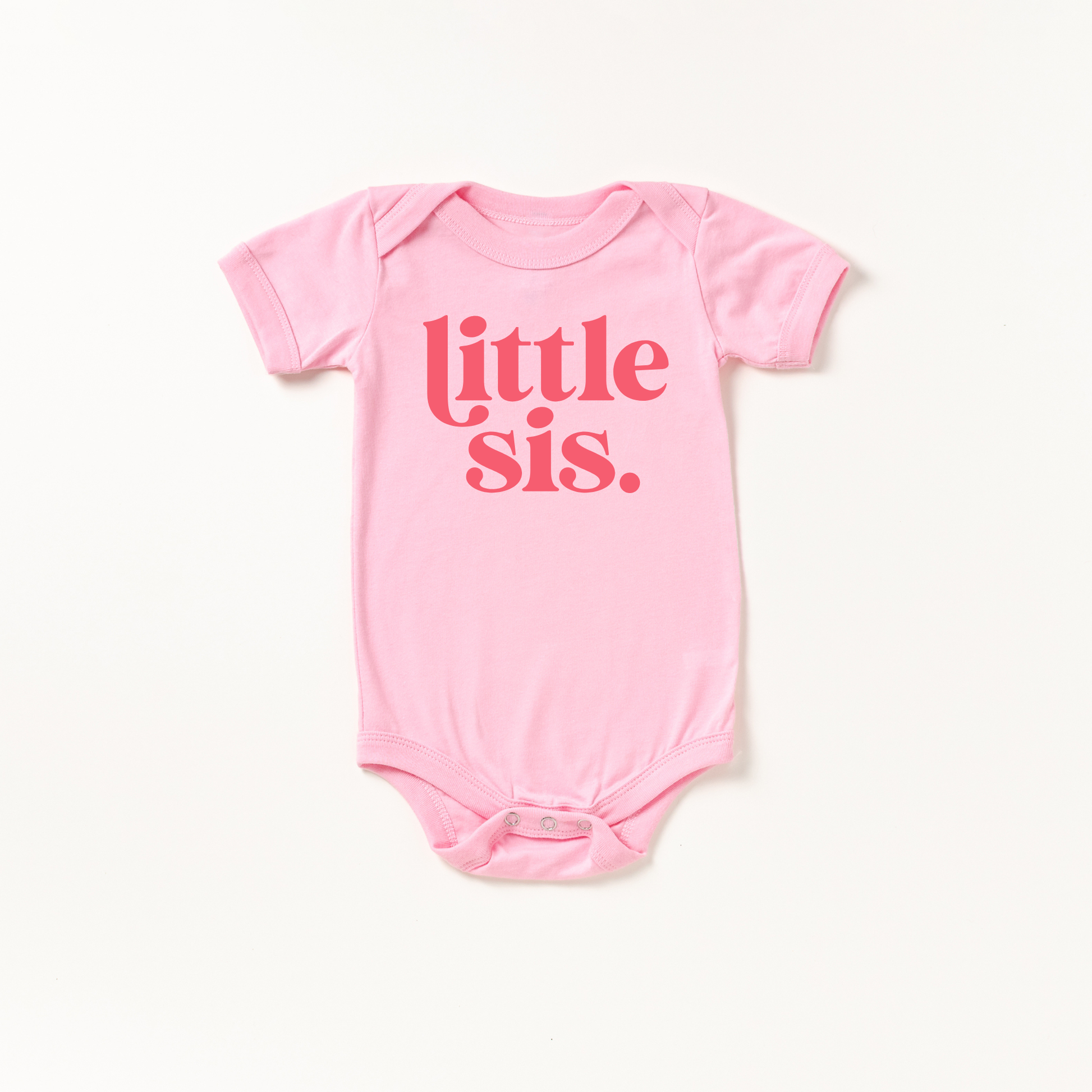 Pink baby onesie with 'little sis' text on a white background