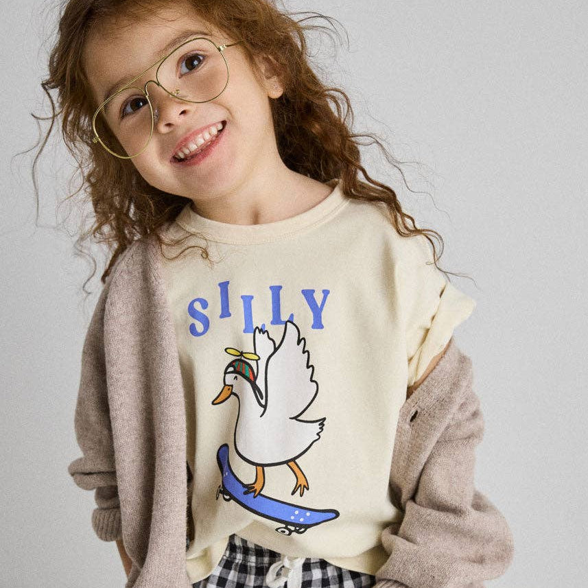 Child wearing a sweater with a duck graphic and 'SILLY' text, standing against a plain background