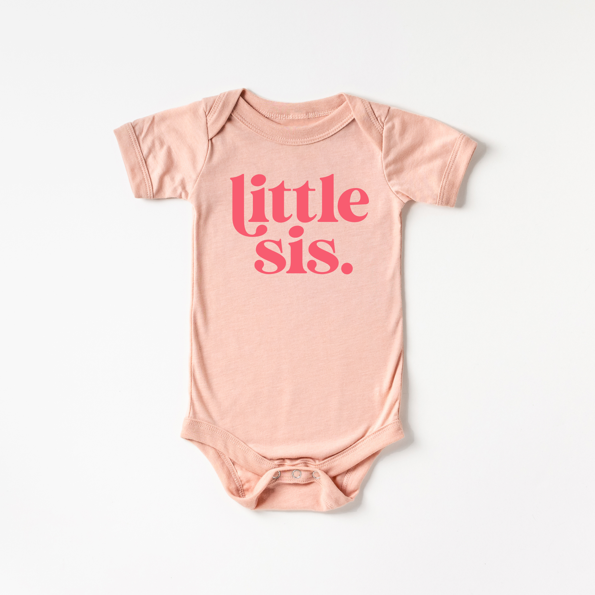 Pink baby onesie with 'little sis' text on a white background