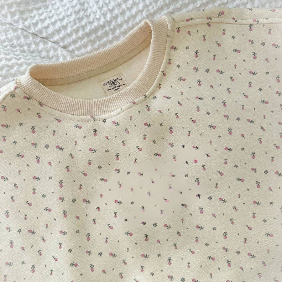 Beige sweatshirt with small floral pattern on a textured white background