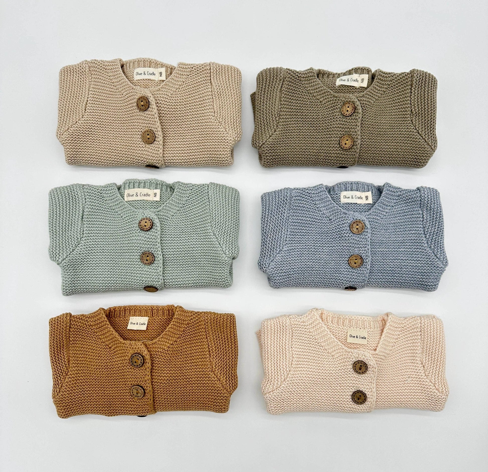 Six folded knit cardigans in different colors on a light gray background