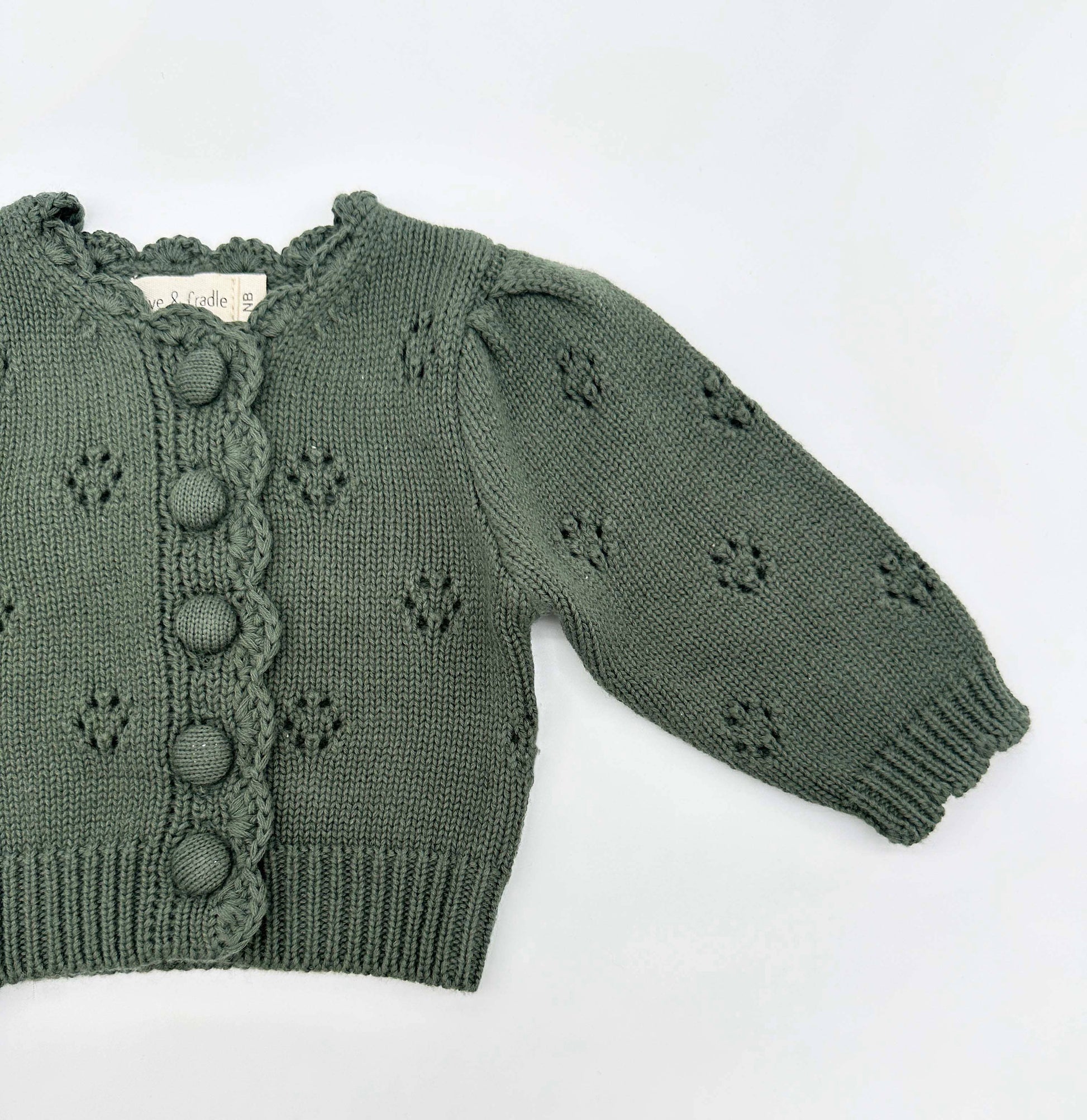 Green knitted sweater with button details on a white background