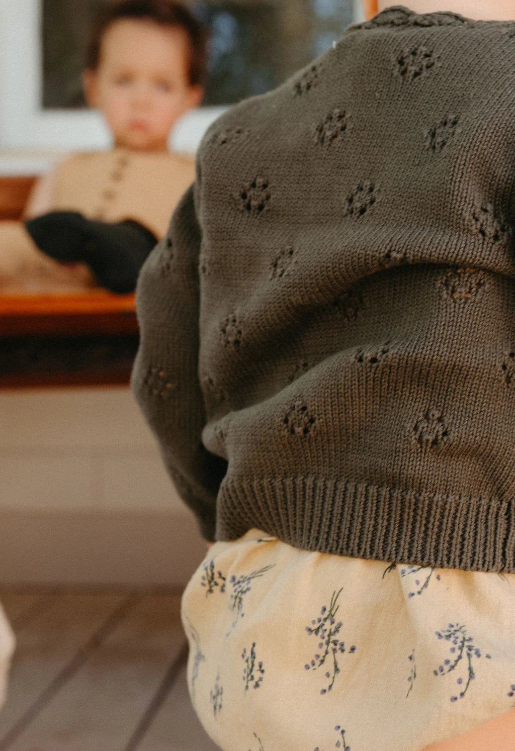 Person wearing a dark green knitted sweater with a blurred background
