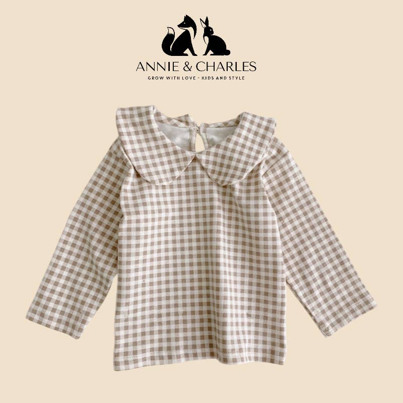 Plaid shirt with bow collar on a beige background, featuring the Annie & Charles logo.