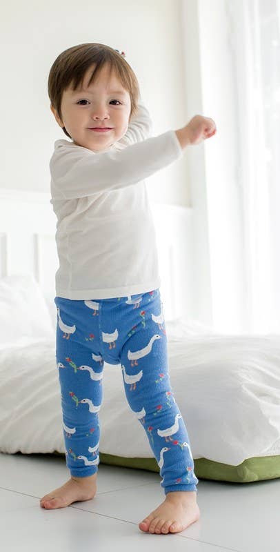 Child wearing blue pajama pants with duck pattern in a bedroom setting