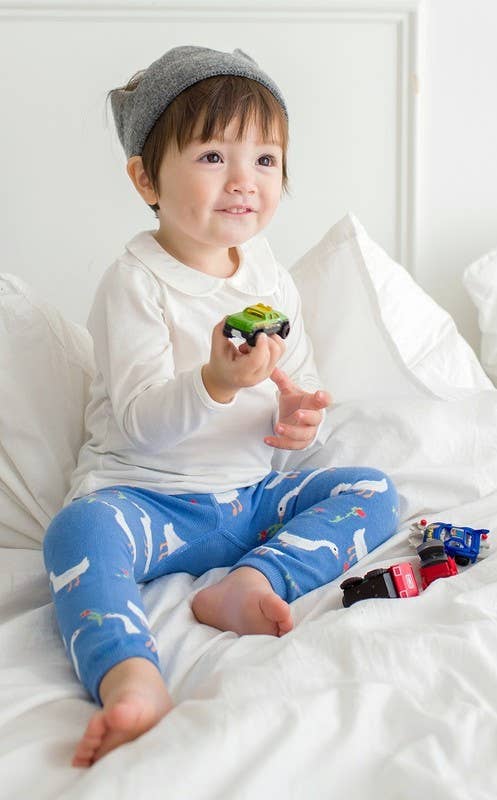 Child holding a toy car on a bed with white bedding