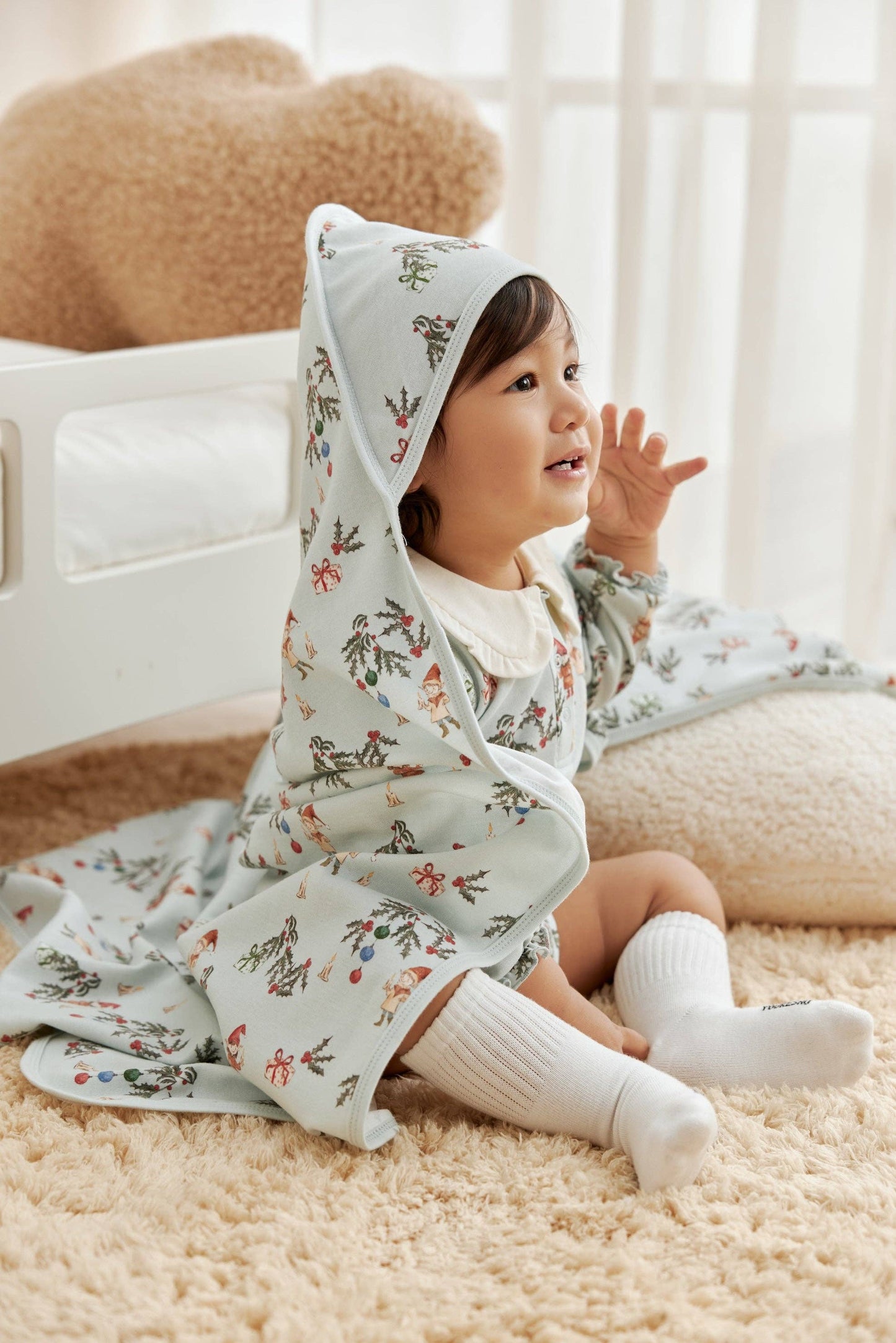 Child wearing a floral outfit with a hood in a cozy indoor setting