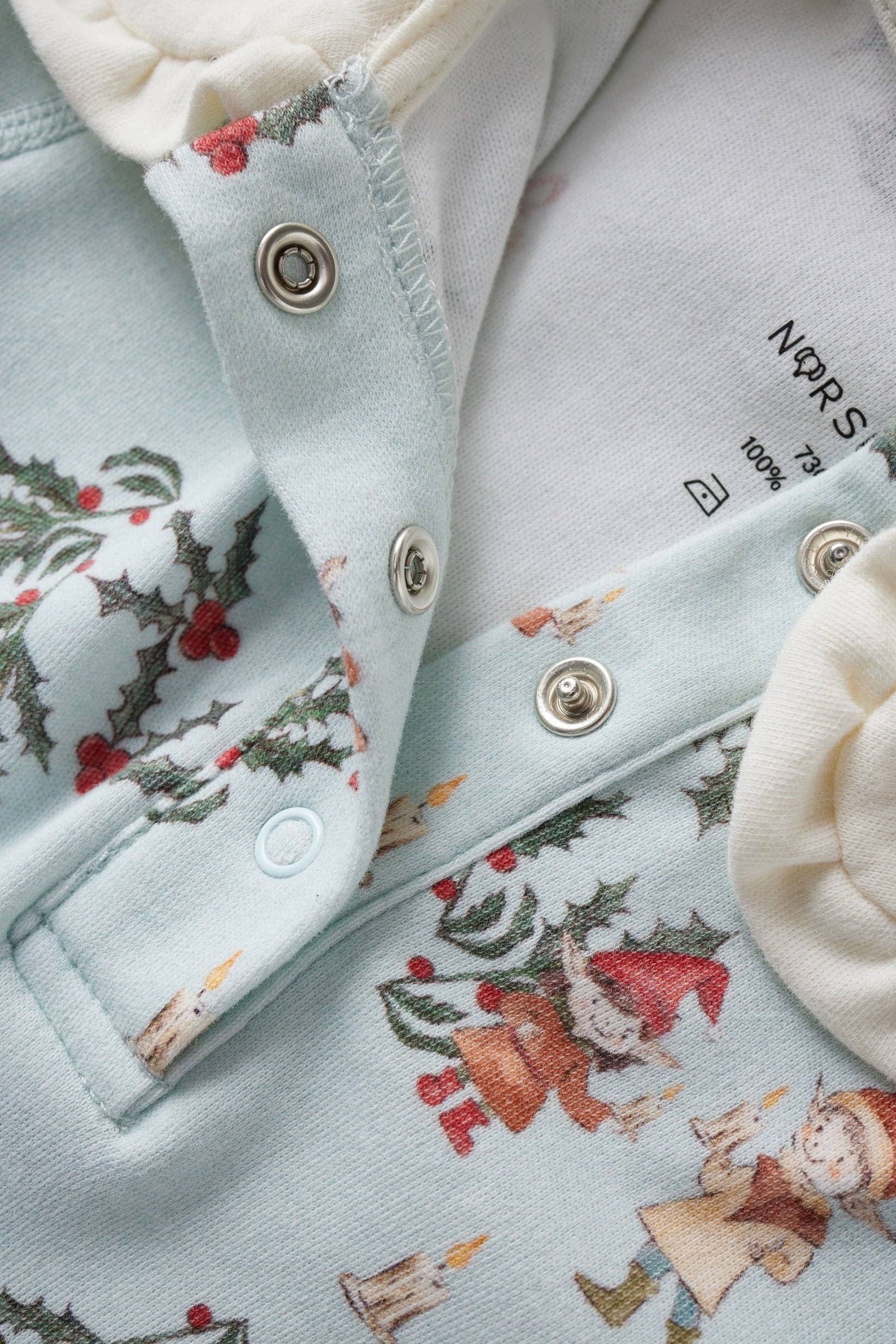 Close-up of a light blue jacket with festive pattern and buttons.