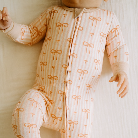 Baby onesie with bow and stripe pattern on a soft surface