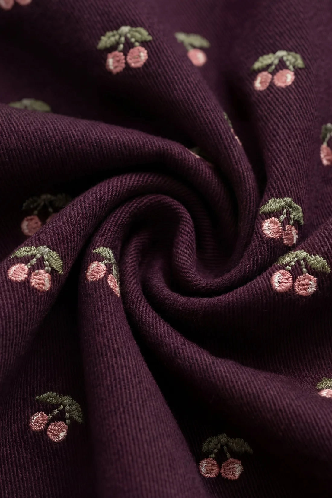 Close-up of dark purple fabric with cherry pattern