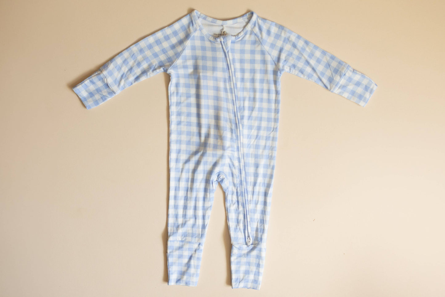 Blue checkered baby onesie on a beige background