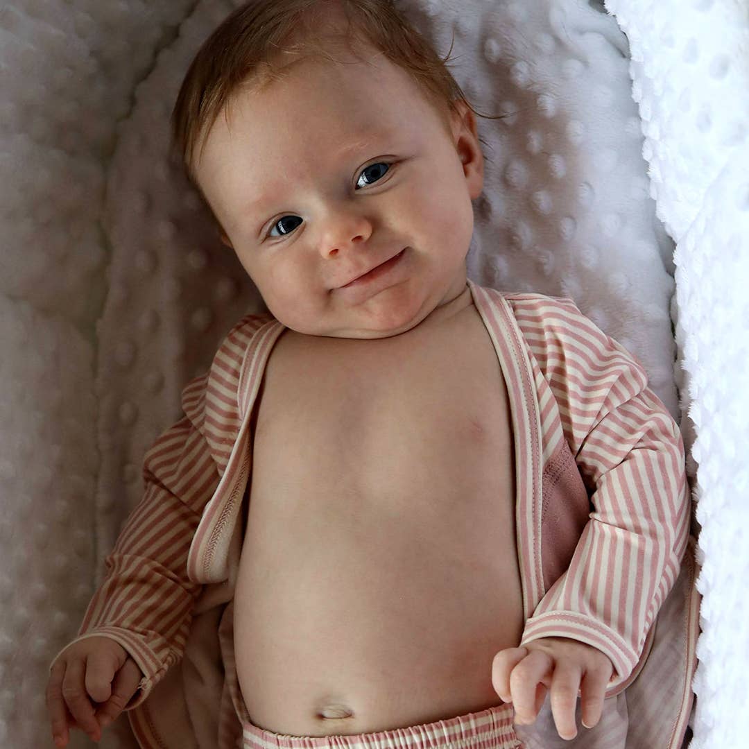 Baby wearing a striped outfit lying on a textured surface