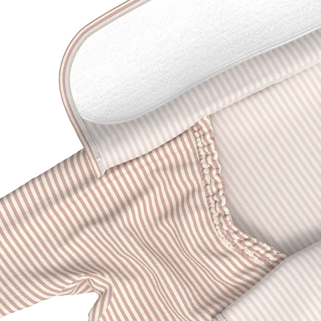 Close-up of a pink and white striped fabric with a mattress corner visible.