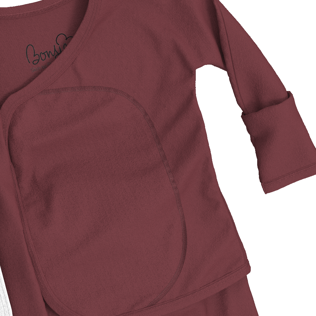 Close-up of a burgundy long-sleeve top with a large front patch pocket and a black script logo on the inner neckline, shown against a white background.