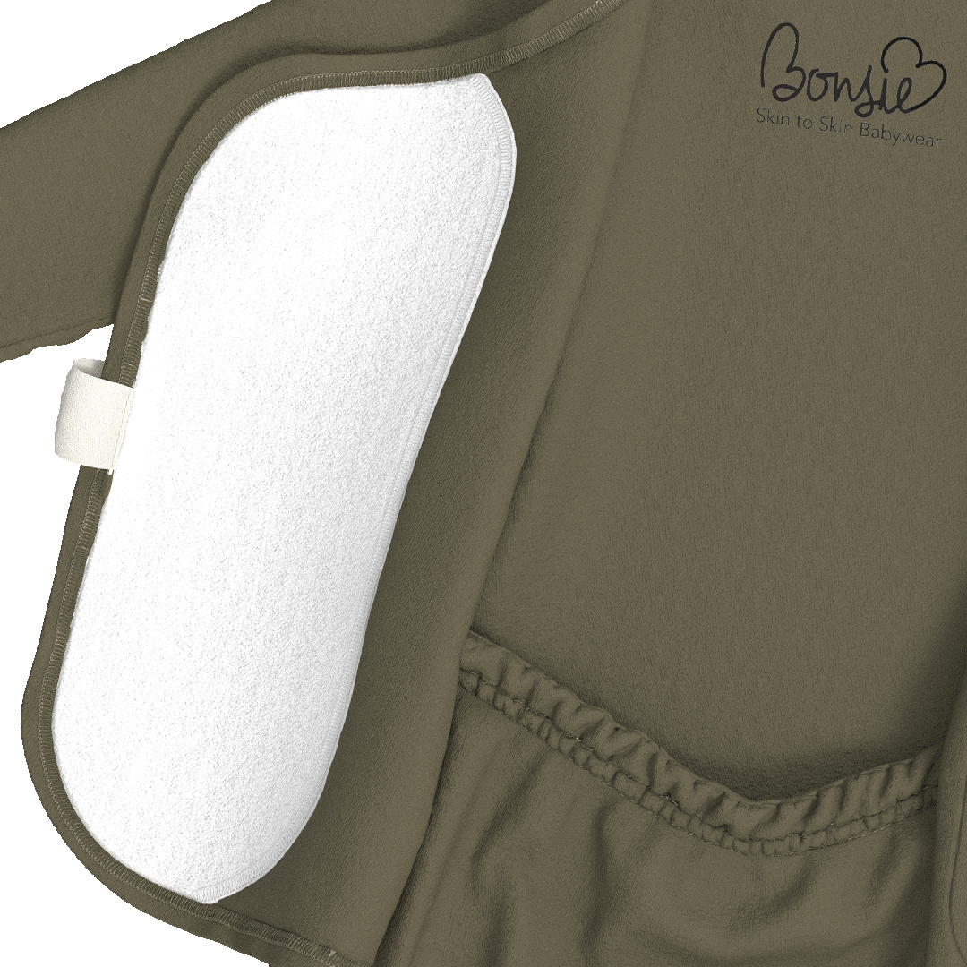 Close-up of an olive green baby garment or cover-up with a white textured insert panel and a small white tag, shown on a white background. The Bonsie logo is printed in black near the upper right.