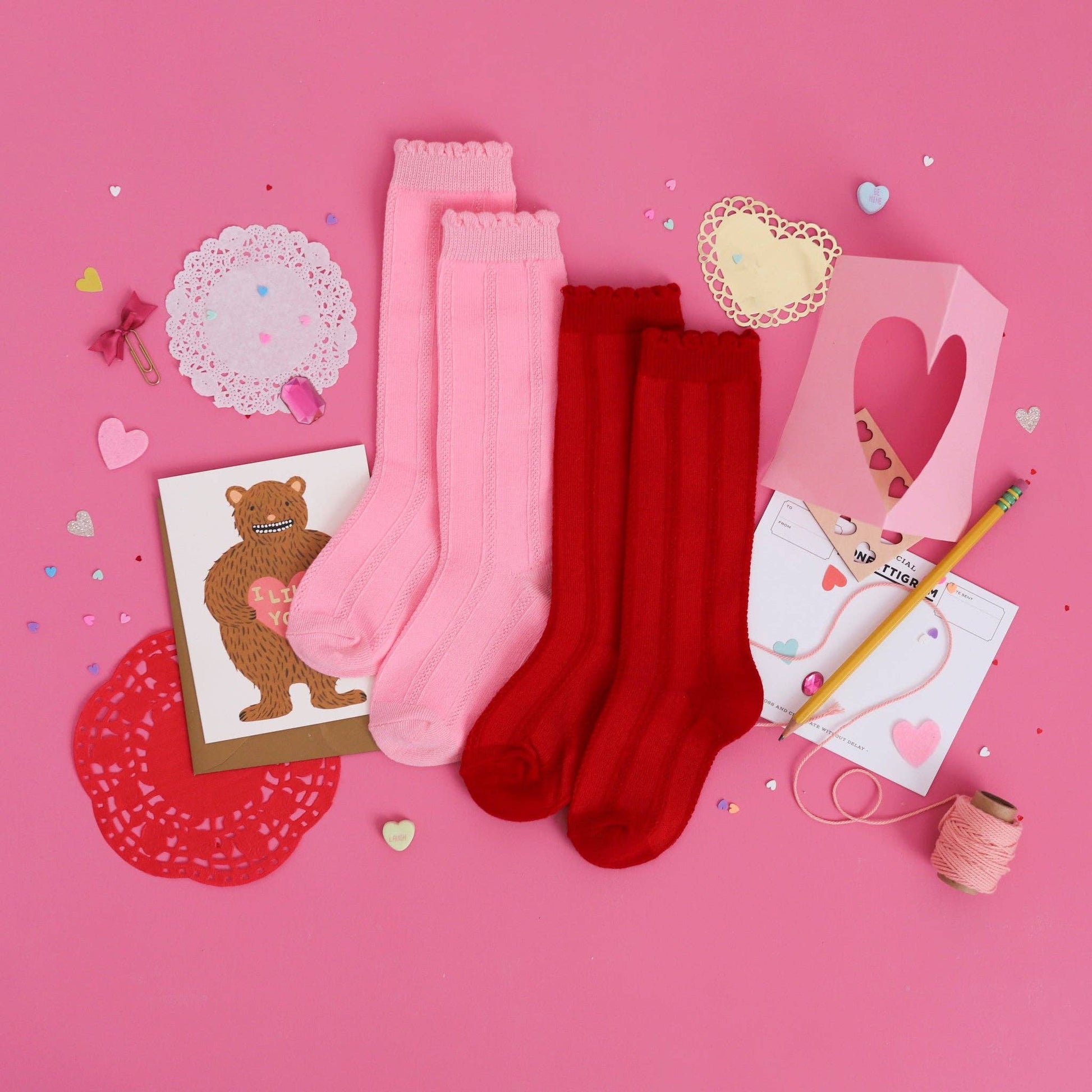 Pink and red socks on a pink background with decorative items.
