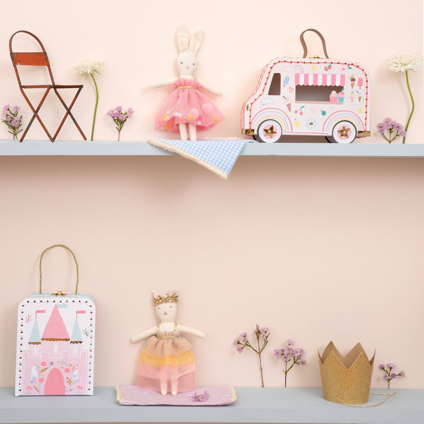 Children's toys and decorative items on a shelf against a pink wall.