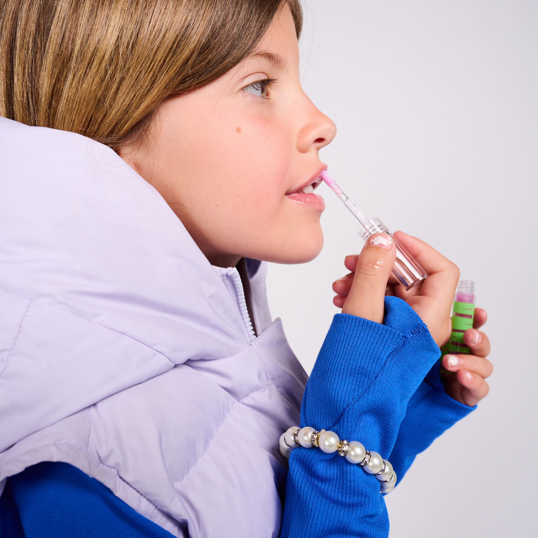 Child applying lip balm with a white background