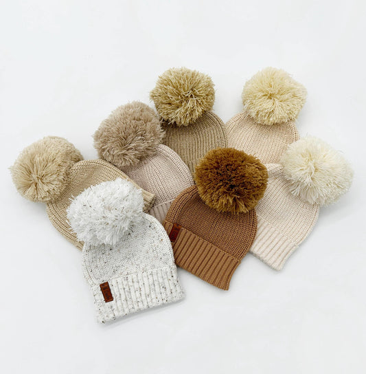 Set of knit beanies with pom-poms on a white background