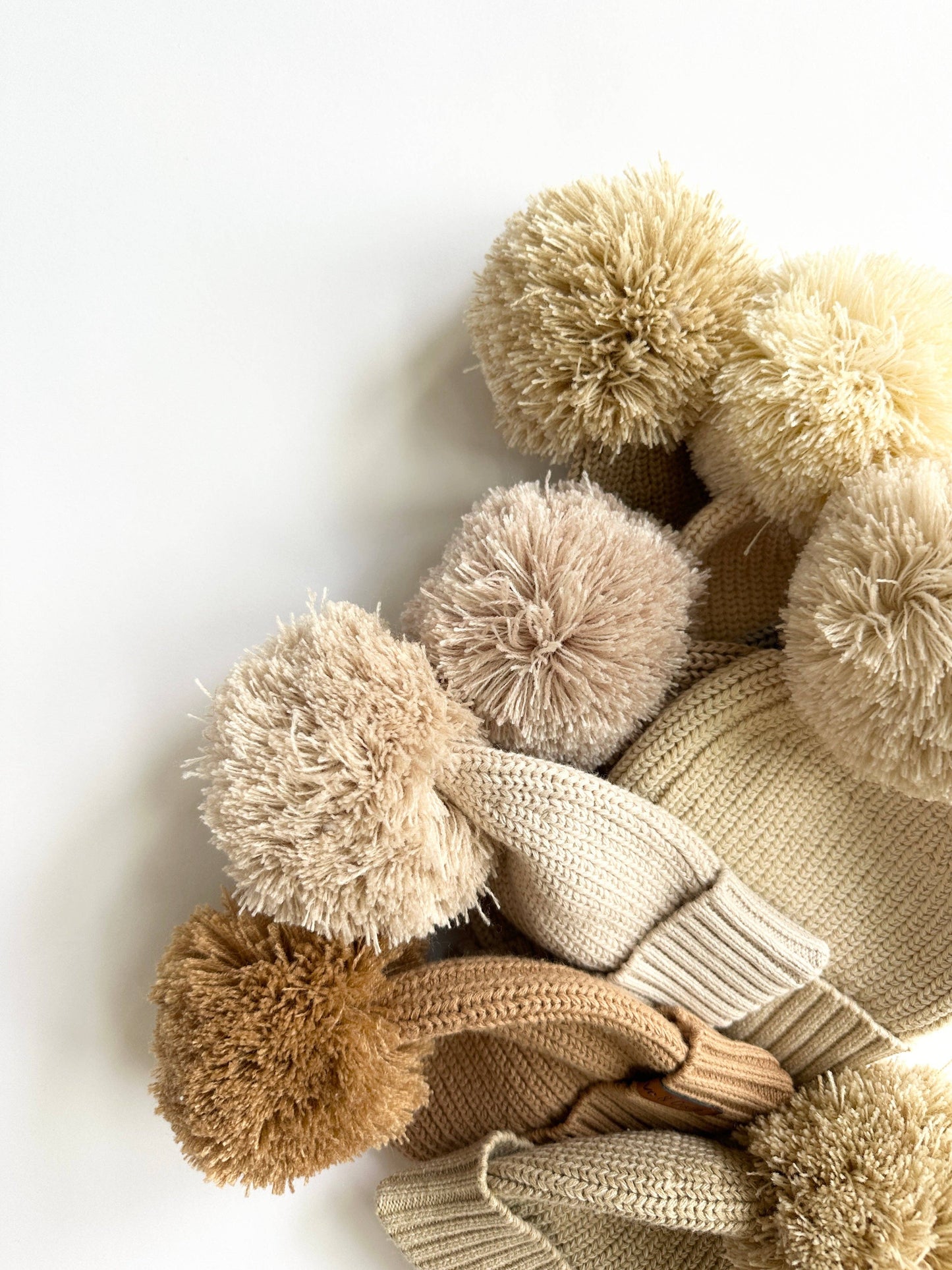 Knitted items with pom-poms on a white background