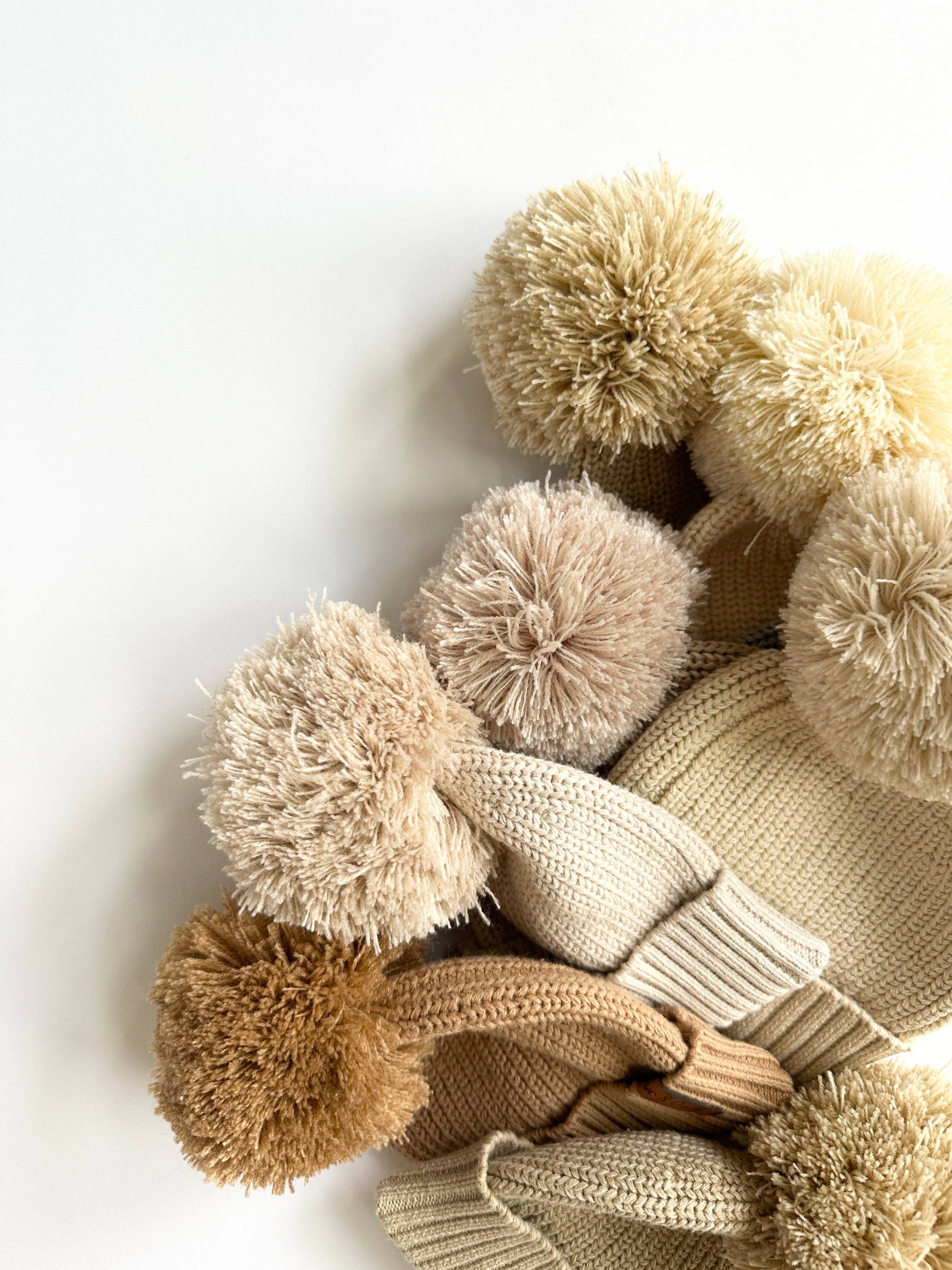 Knitted items with pom-poms on a white background