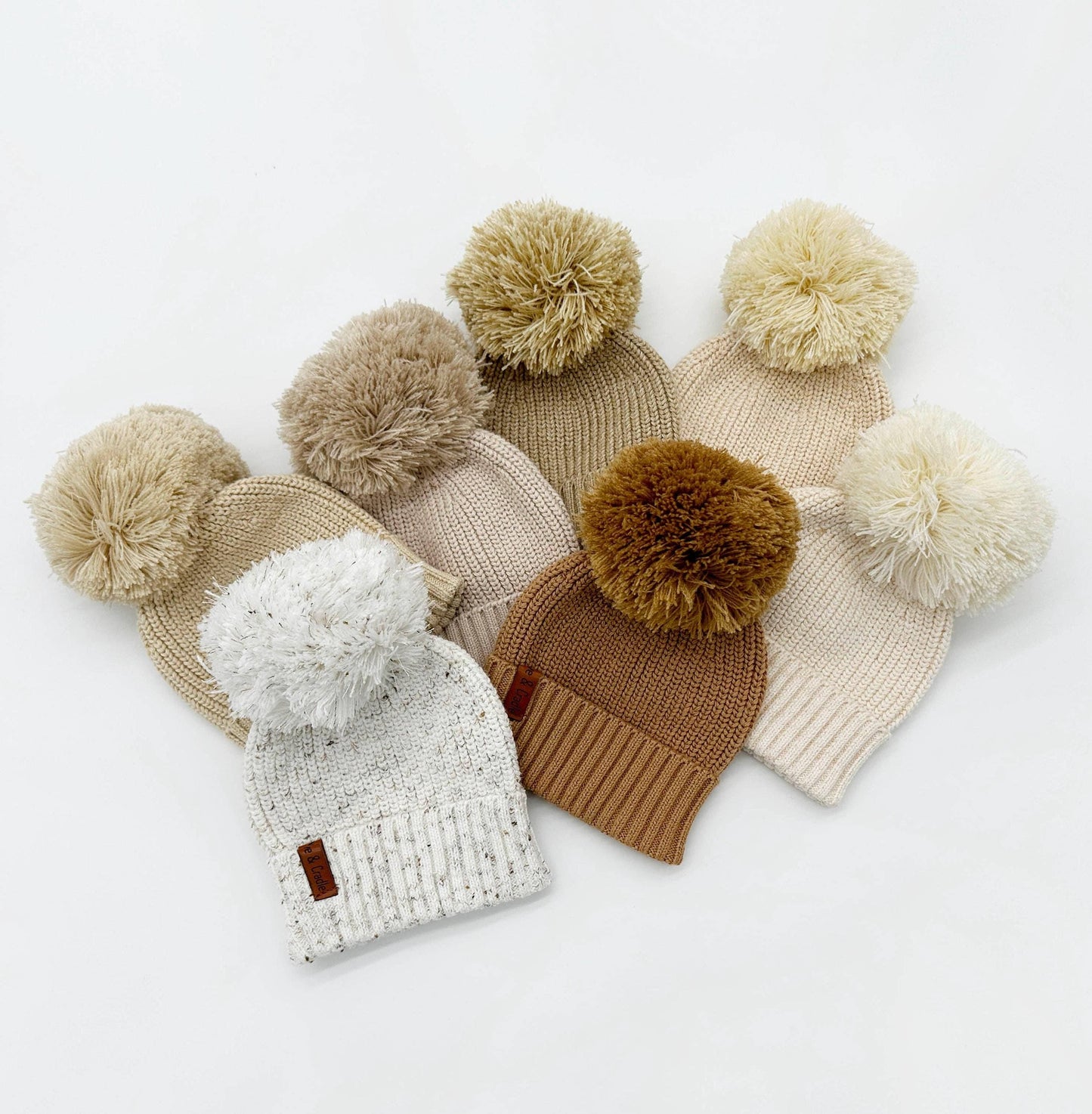 Set of knit beanies with pom-poms on a white background