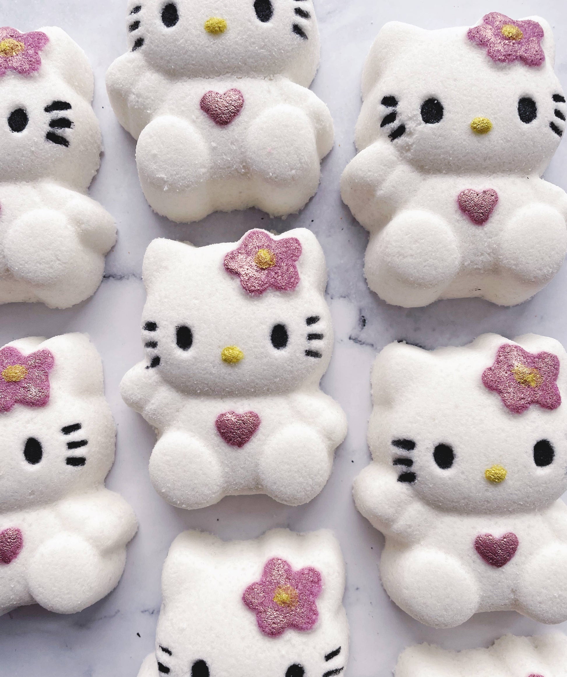 White Hello Kitty marshmallows with pink flowers and hearts on a white background