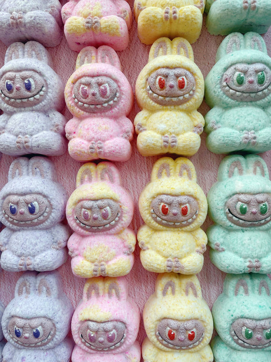 Row of colorful plush toys with cartoonish faces on a pink background