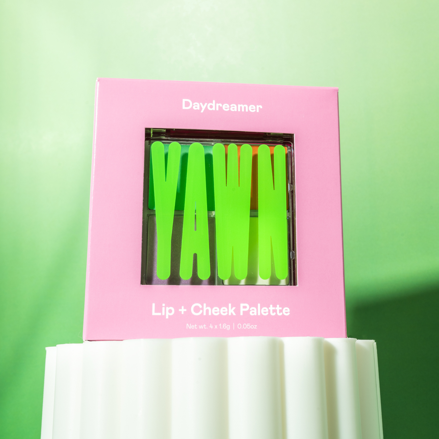 Pink 'Daydreamer' lip and cheek palette with green shades on a green background