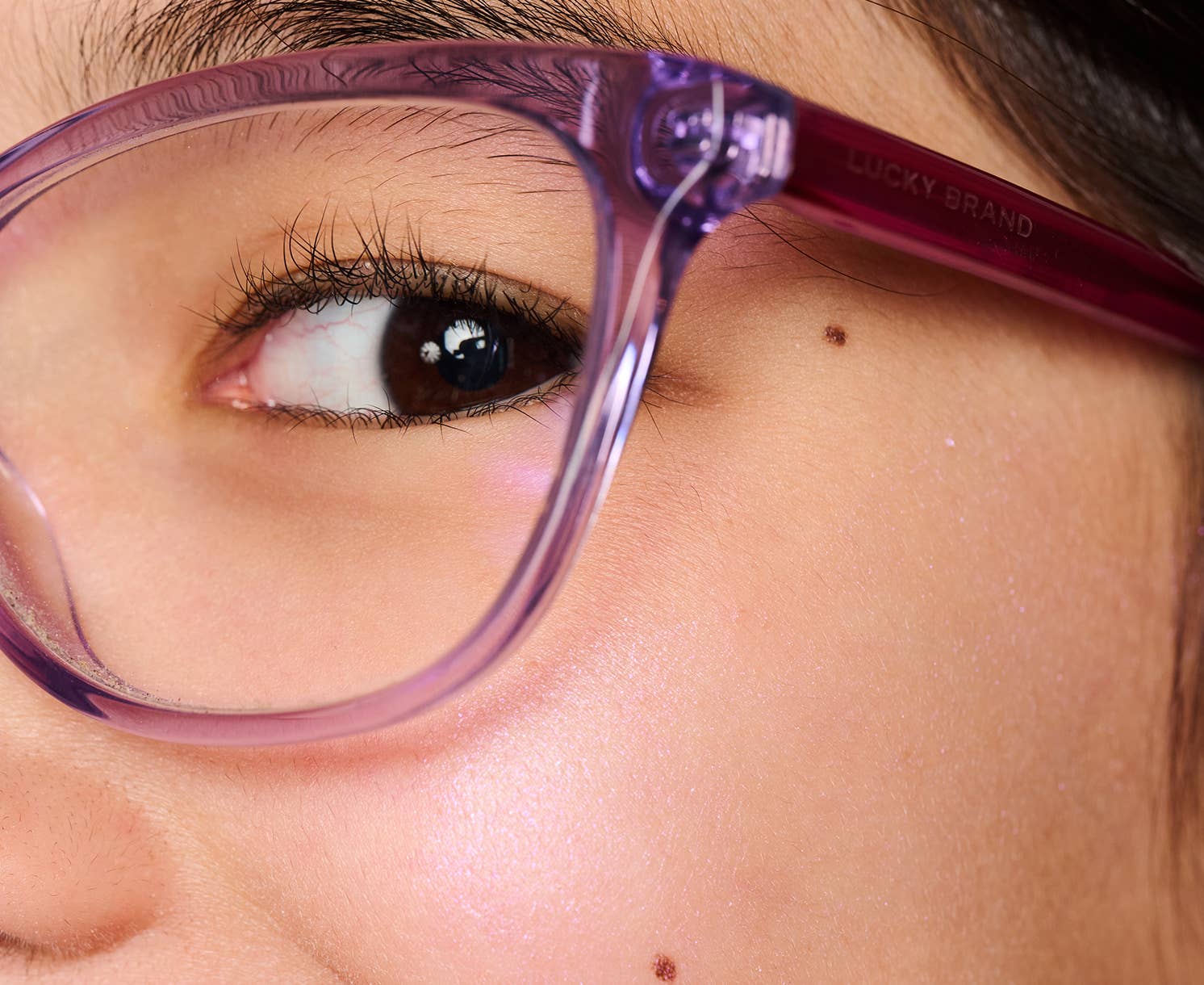 Close-up of a person wearing purple Lucky Brand glasses.