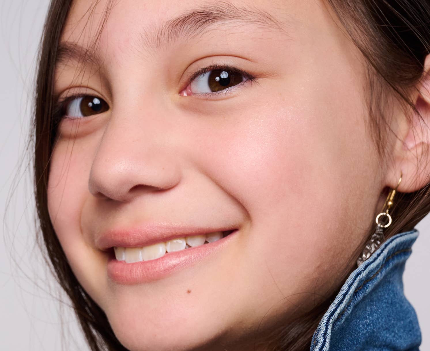 Close-up of a person wearing earrings with a neutral background