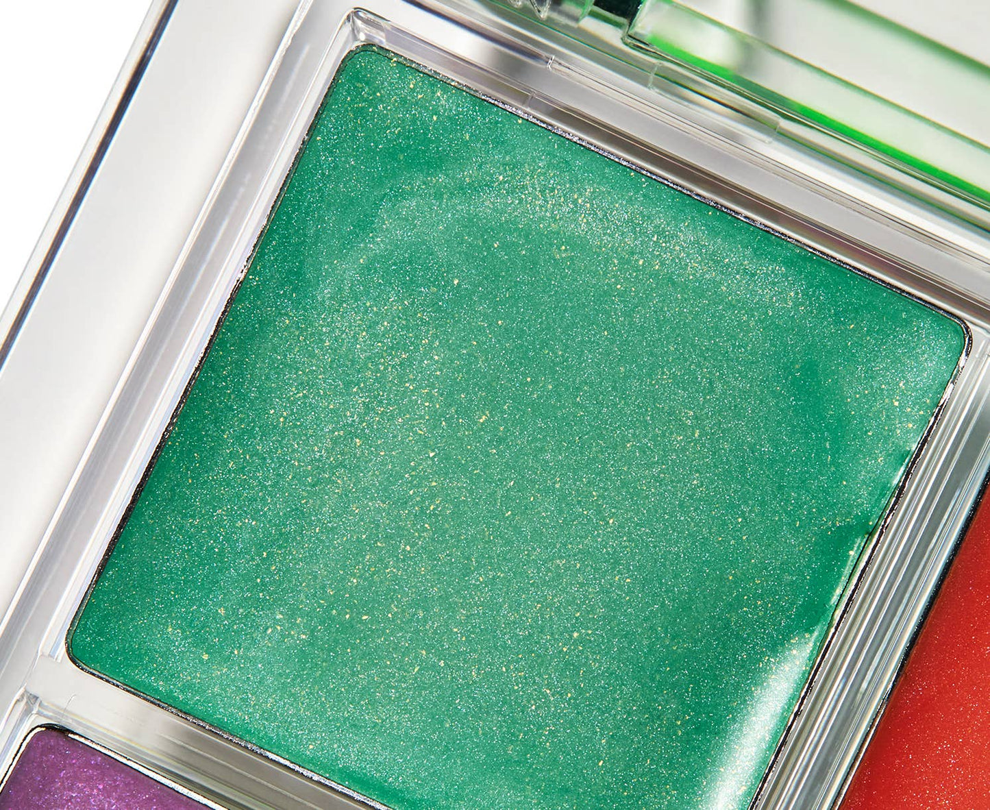 Close-up of a green eyeshadow compact with a silver frame.