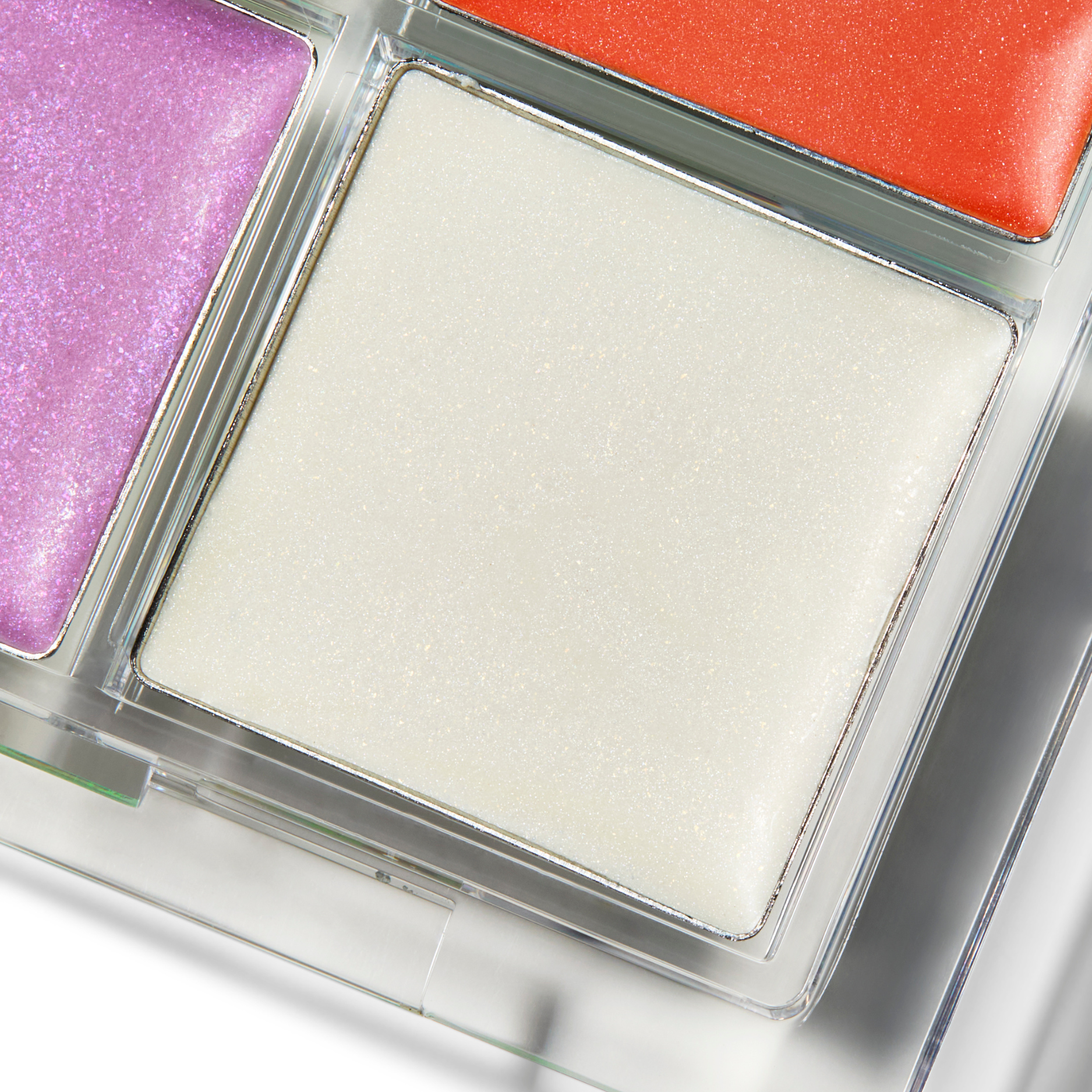 Close-up of a makeup palette with white, purple, and red shades.