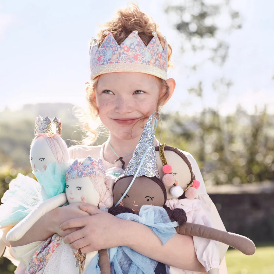 Child wearing a floral crown holding plush toys outdoors