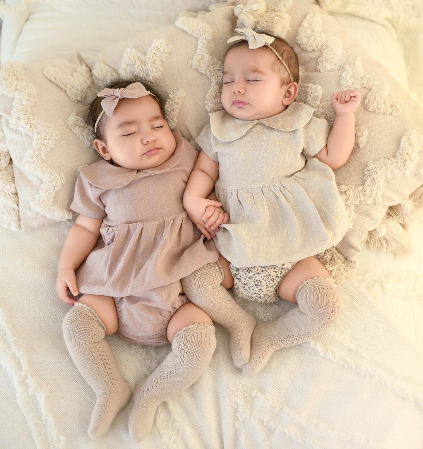 Two babies in matching outfits lying on a soft surface